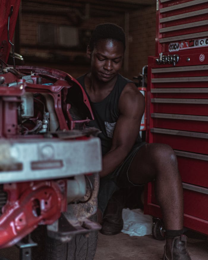 Focused young mechanic inspecting an engine in a workshop, showcasing automotive expertise.